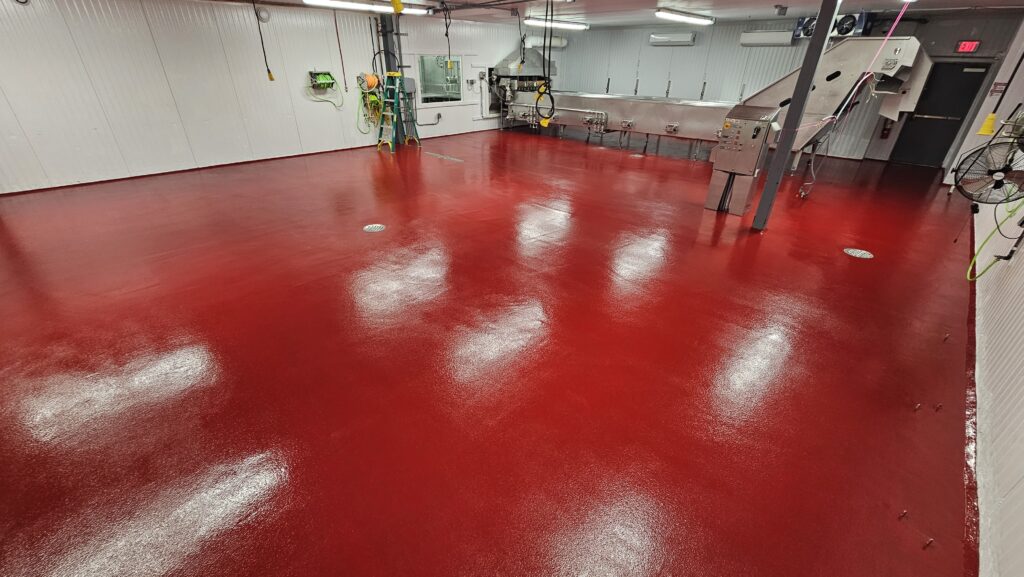 A textured, glossy, red slip-resistant floor is used in a food manufacturing facility.