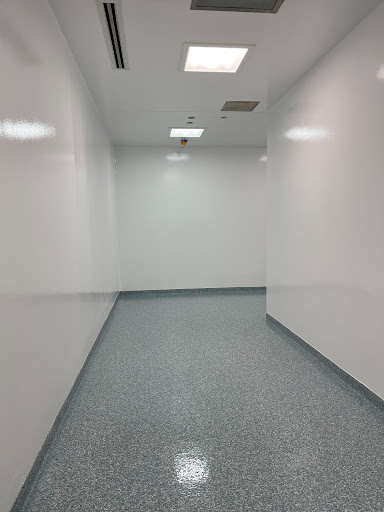 A hospital hallway has seamless, non-porous flooring that creates a continuous surface for easy cleaning and safe foot traffic.